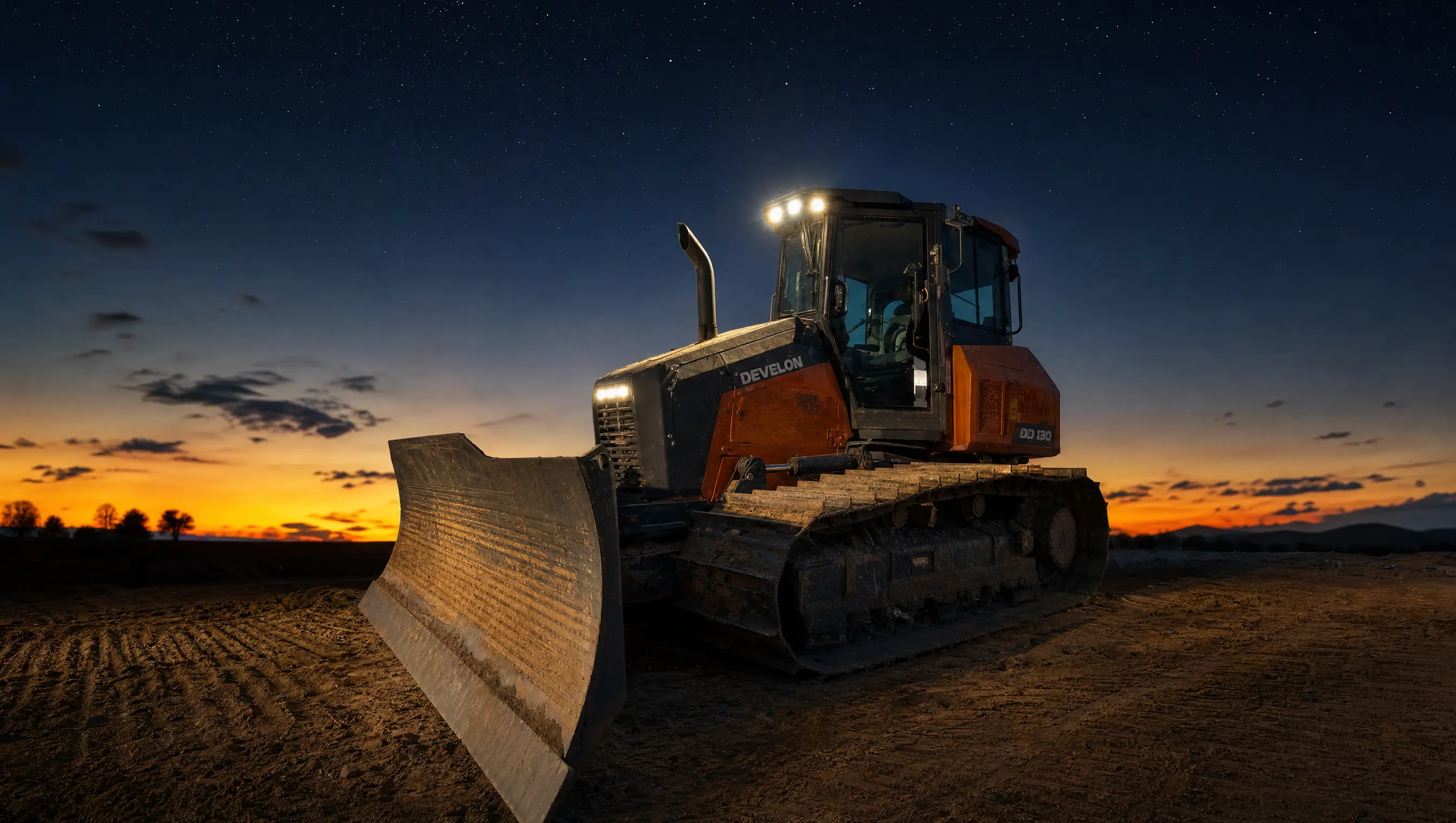 A DEVELON DD130 dozer at rest against a starry post-sunset sky, work lights on