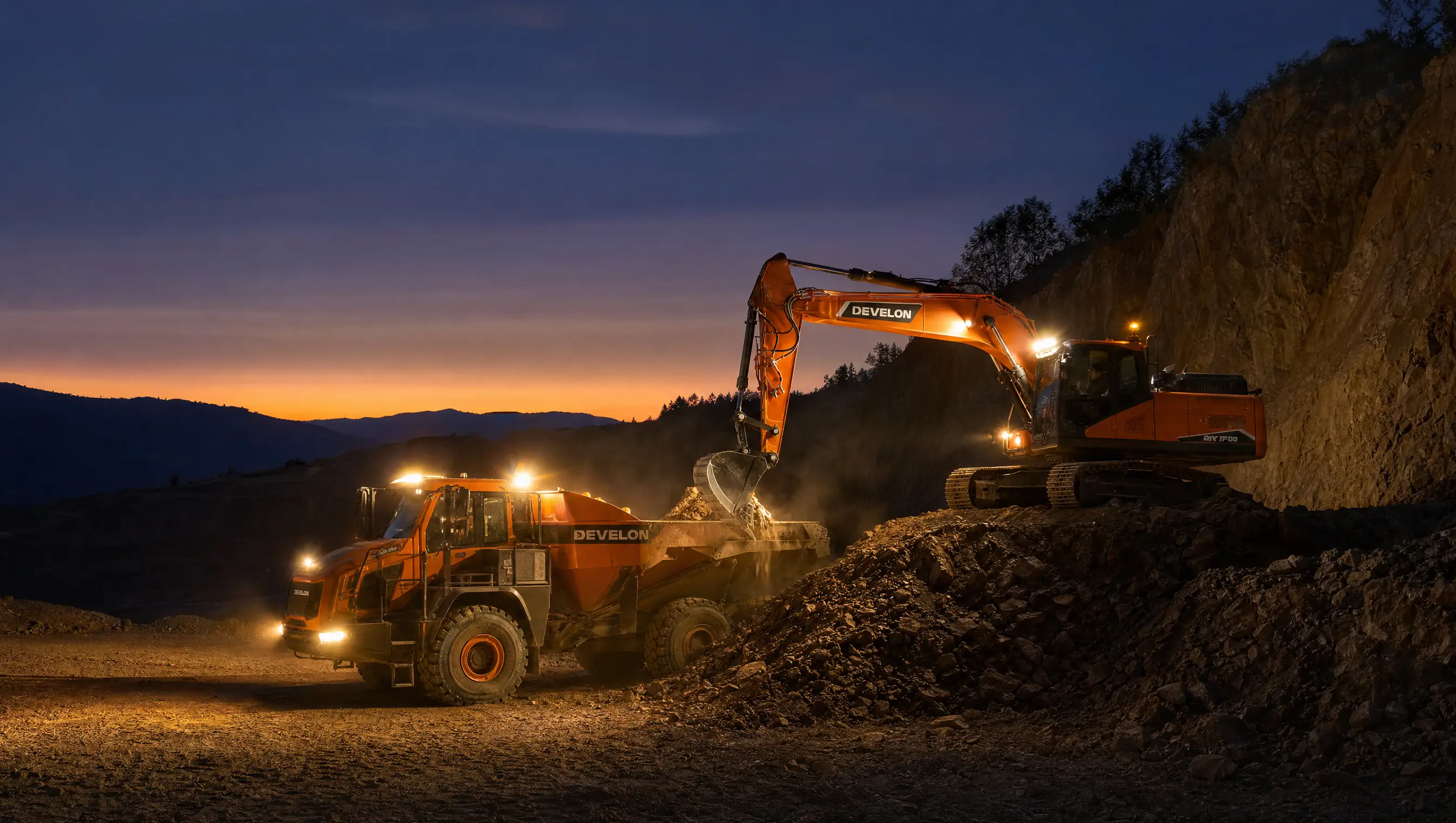 A DEVELON excavator loading a dump truck at dusk with work lights blazing